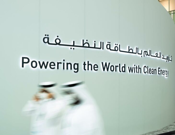 Powering the world with clean energy slogan on big wall, with two motion blurred people in front 