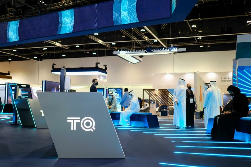 TQ logo in front with blue conference stand behind