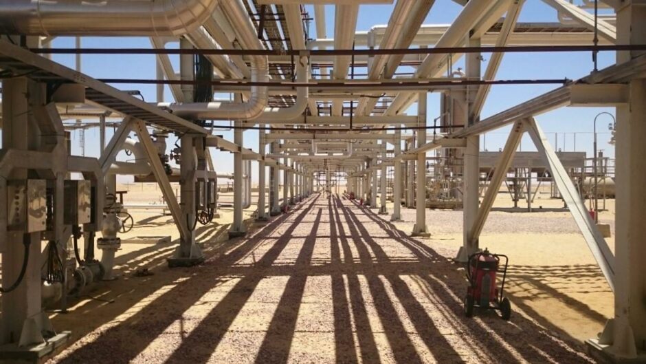 Pipes run over head, casting shadows on the ground