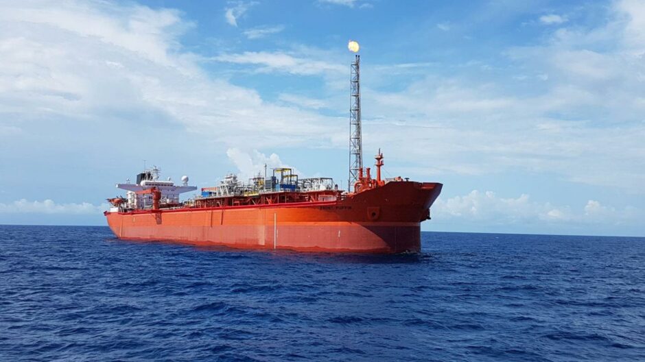 An orange FPSO floats on a blue sea