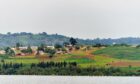 Lake in the foreground, green rolling hills behind