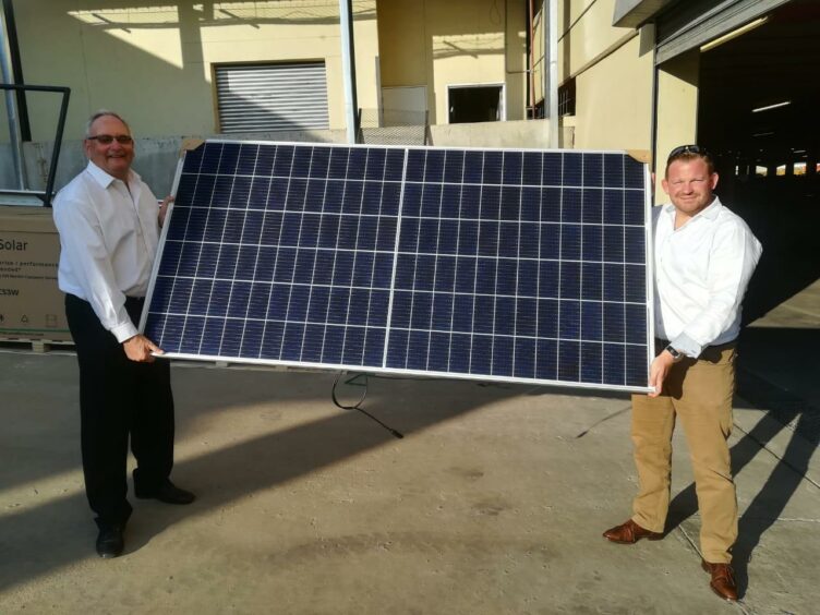 Two men hold a solar panel
