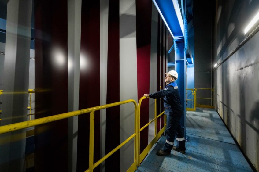 Man stands on gangway looking at industry