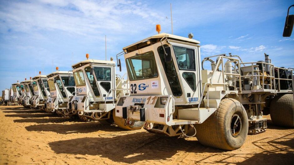 Seismic trucks lined up on the sand