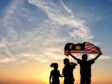 Silhouette of children waving the national flag in conjunction with Malaysia Independence Day.