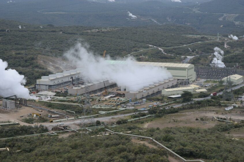 A building emits steam in a green landscape