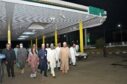 People walking in a fuel station at night