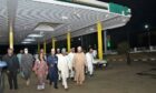 People walking in a fuel station at night