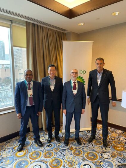 Four men stand in a hotel room