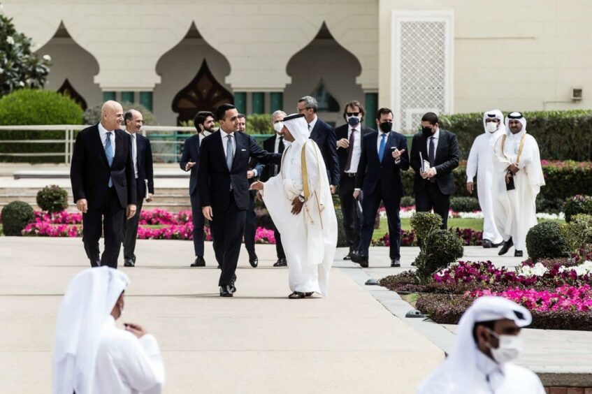 Men walk along talking in garden