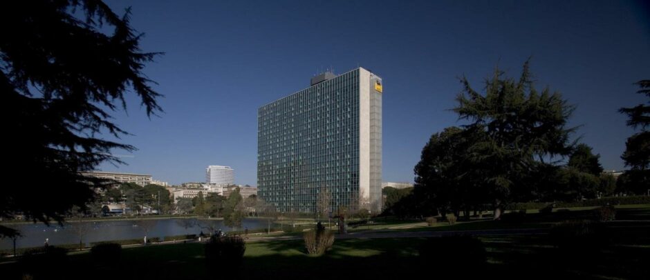 Big office building between trees and next to a lake