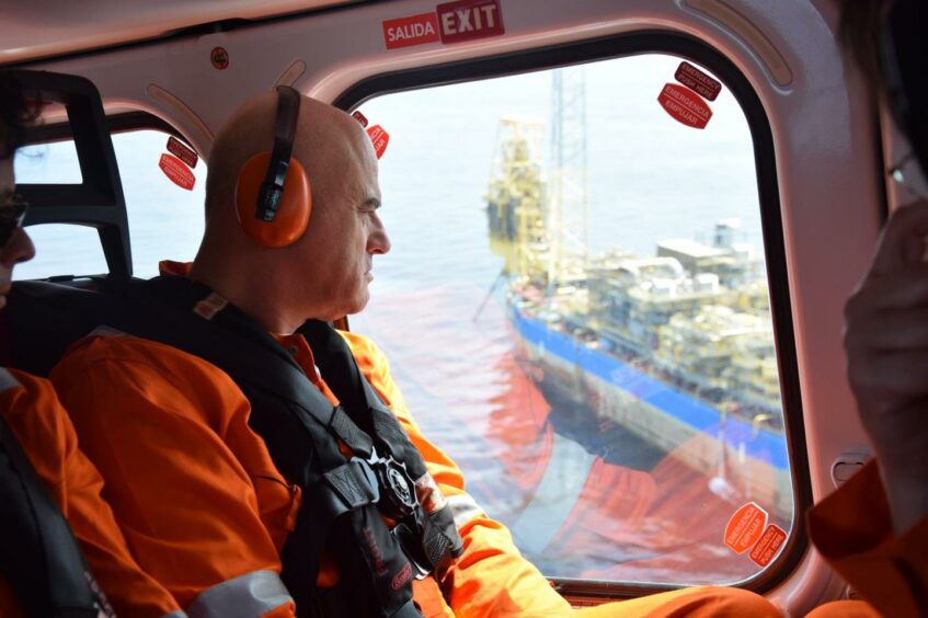 Man in orange boilersuit looks out of helicopter window
