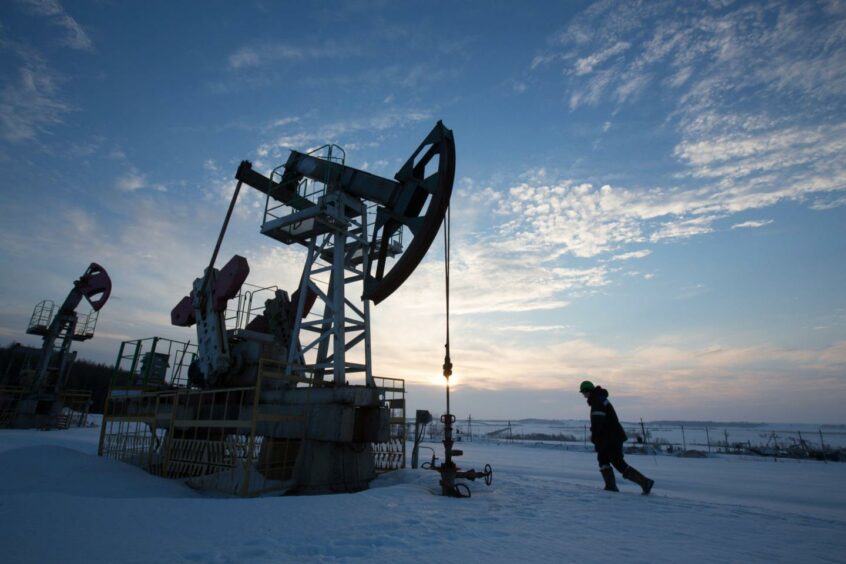 An oil worker inspects a pumping jack, also known as a 'nodding donkey,' during drilling operations in an oilfield operated by Bashneft PAO in the village of Otrada, 150kms from Ufa, Russia, on Saturday, March 5, 2016. Photographer: