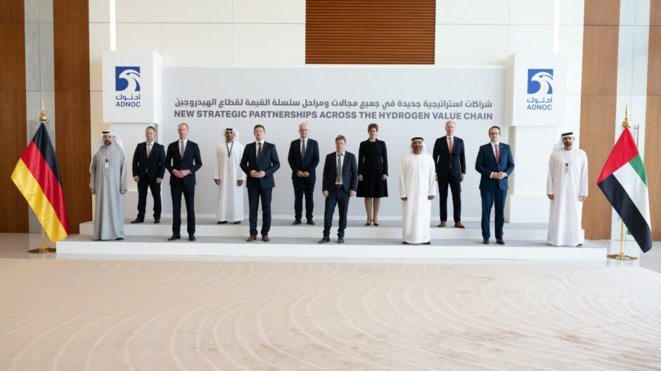 Men stand on steps between German and UAE flags