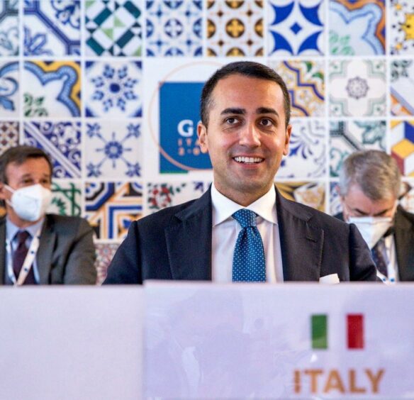 Man smiling with tie, Italian flag in foreground 