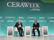 Two men sit on a podium under CERAWeek sign