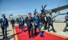 Two men walk down a red carpet in front of Iraq Air Force plane