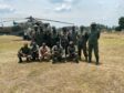 Group of soldiers stand in front of helicopter