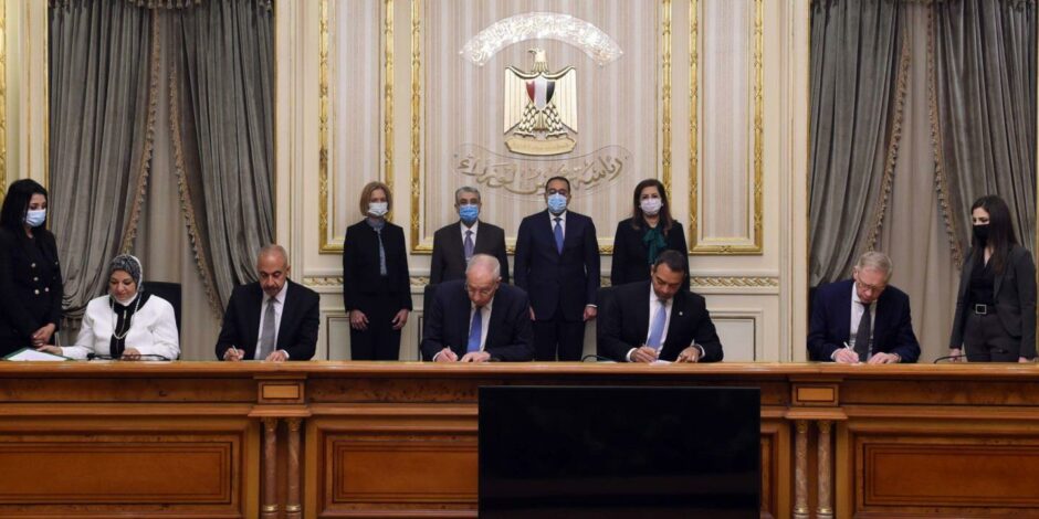 People signing a document at a big desk