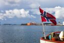 Norway flag at dramatic sky on industrial background.; Shutterstock ID 1328177468; purchase_order: energy voice; job: march 2022 well slot