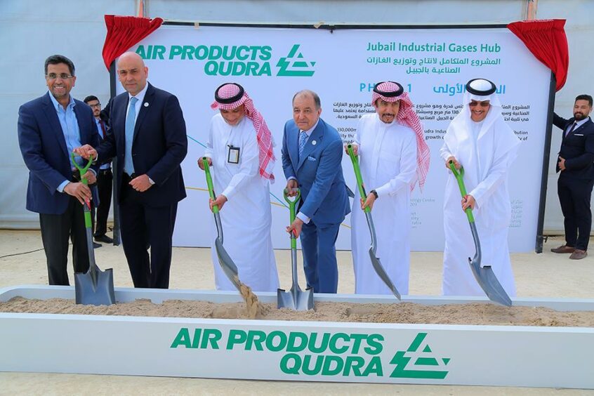 Men with shovels in front of Air Products Qudra sign