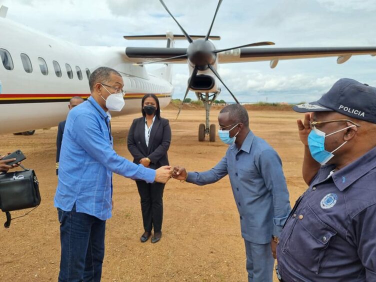 Two men greet in front of an aeroplane turbine