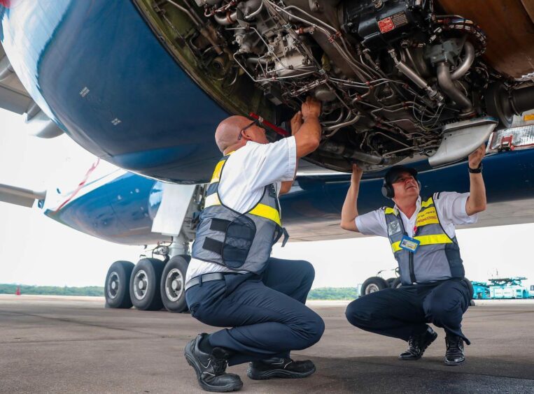 Two men work underneath a plane