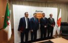 Four men against Sonatrach backdrop with flags