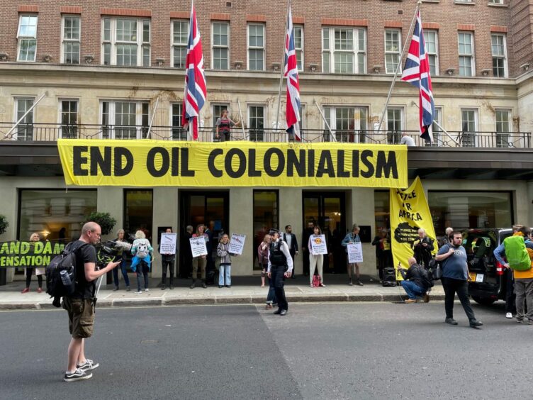 End Oil Colonialism sign above a hotel entry