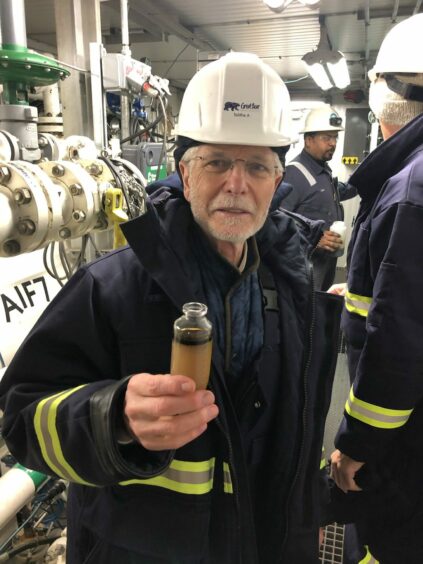 Man in hard hat holds oil sample 