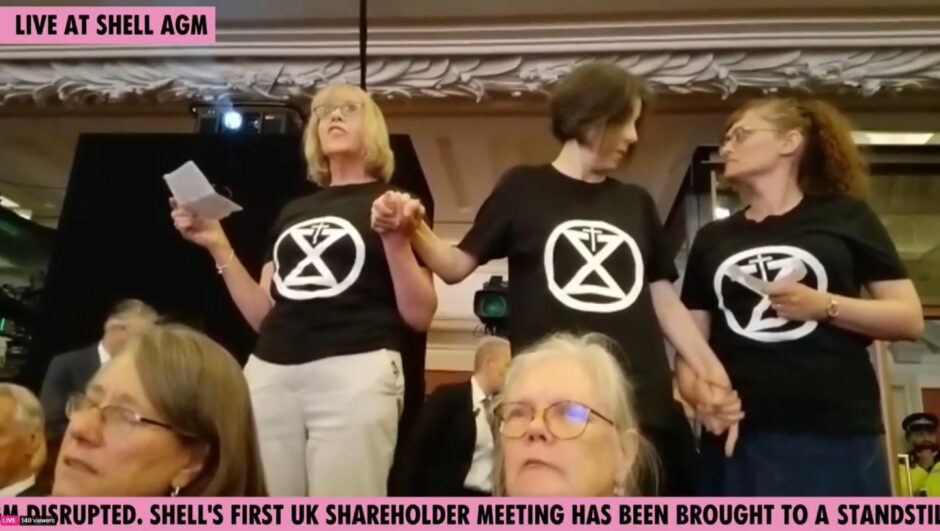 Three protesters in T shirts hold hands