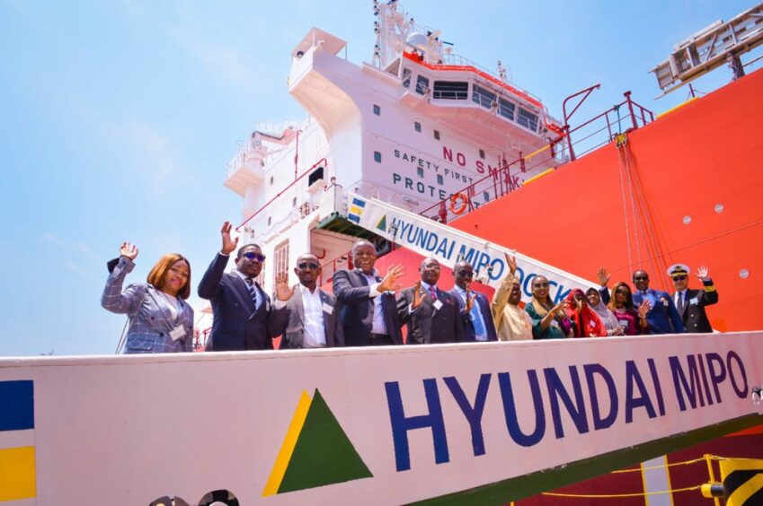 Hyundai barrier in foreground with people and orange ship behind 