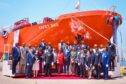 Group stand in front of orange ship
