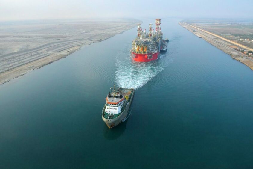 A tug pulls the Energean FPSO along a waterway