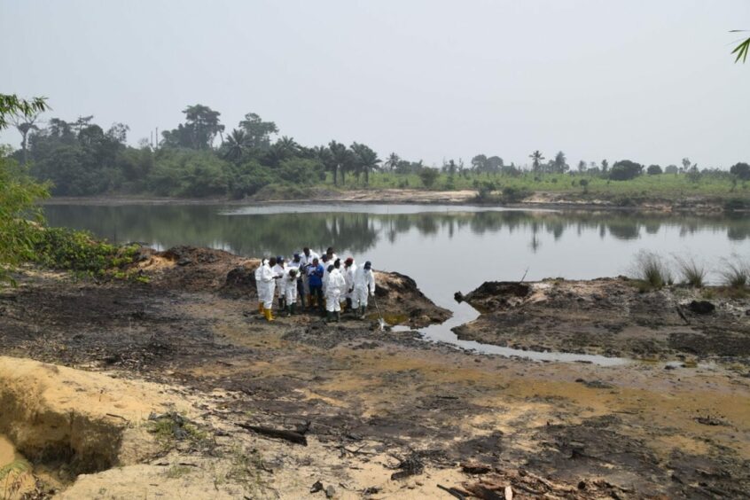 People in boilersuits stand by water