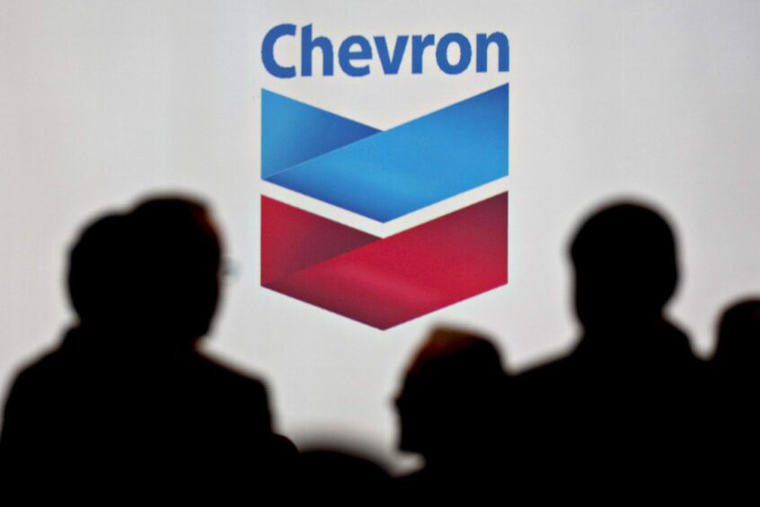 Attendees stand near Chevron Corp. signage during the World Gas Conference in Washington, D.C., U.S, on Tuesday, June 26, 2018.