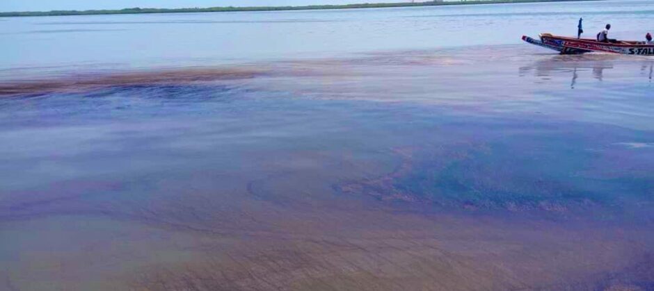 Oil spill on water with boat in top right corner