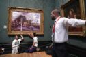 Protesters from Just Stop Oil climate protest group, glue their hands to the frame of John Constable's The Hay Wain after first having covered the painting with their own picture inside the National Gallery, London. Picture date: Monday July 4, 2022.