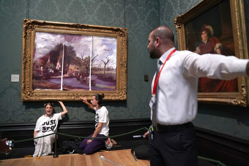 Protesters from Just Stop Oil climate protest group, glue their hands to the frame of John Constable's The Hay Wain after first having covered the painting with their own picture inside the National Gallery, London. Picture date: Monday July 4, 2022.