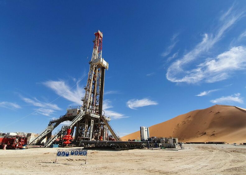 Rig on sand under a blue sky with wispy clouds