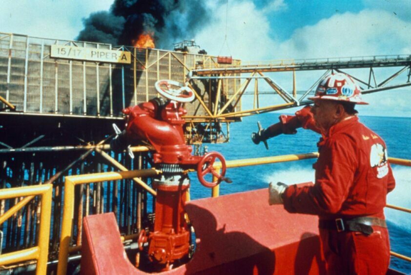 Red Adair working on the site of the Piper Alpha disaster in his trademark red overalls.