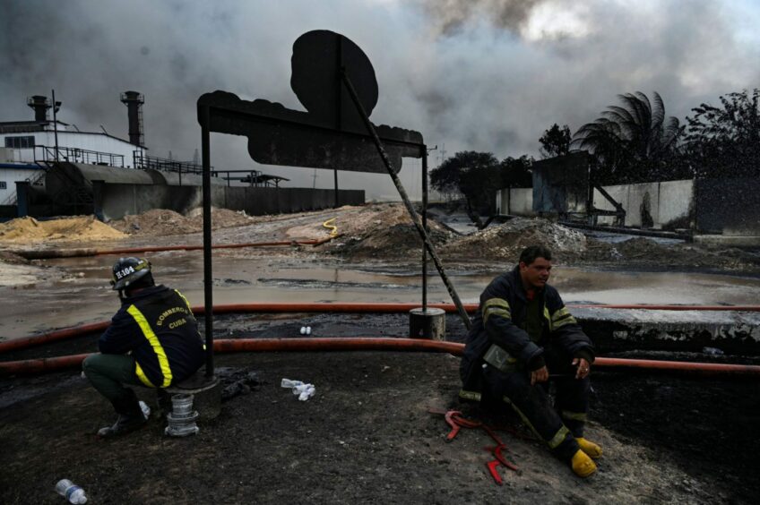 Firefighters rest in the area where the massive fire at a fuel depot sparked by a lightning strike occurred in Matanzas, Cuba, on August 9, 2022.  Photographer: Yamil Lage/AFP/Getty Images