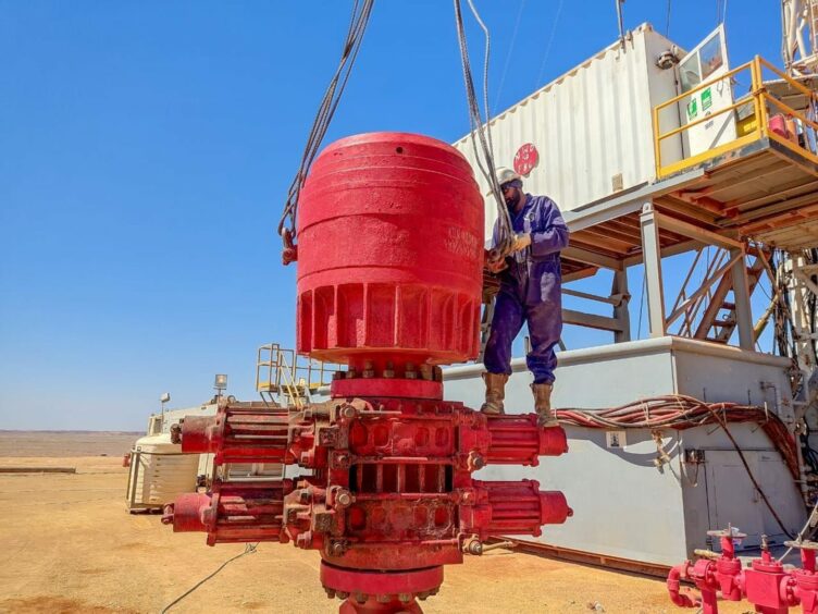 Man stands on big red wellhead