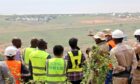 Group of people in safety vests look across field