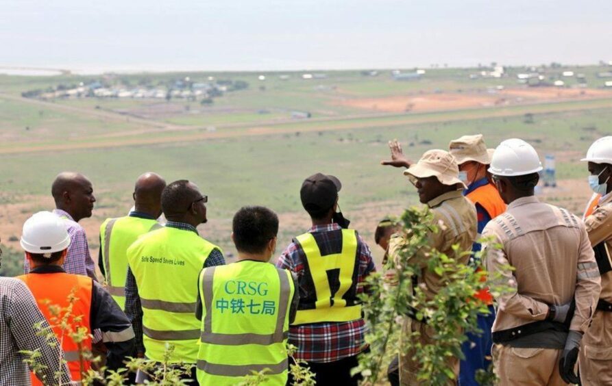 Group of people in safety vests look across field