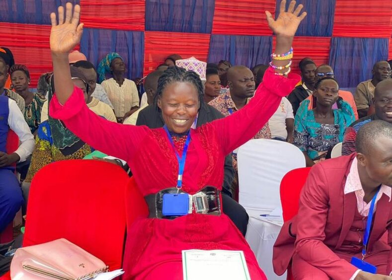 Woman in red raises hands to sky in celebration