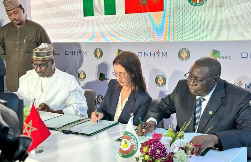 Three people sign documents at a table