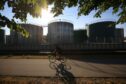 Bicyclist in front of oil storage tanks