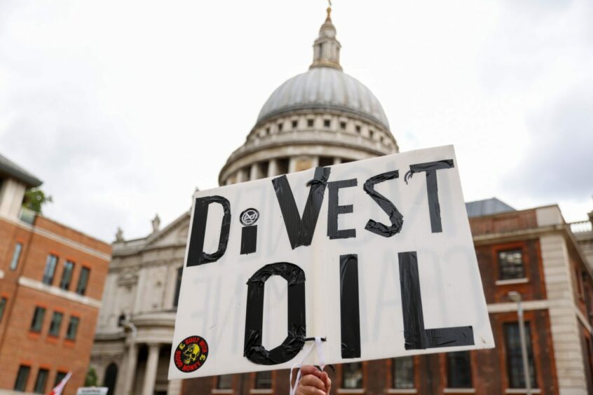 A climate activist from Extinction Rebellion holds a placard during their 'Blood Money March' protest as part of their Impossible Rebellion campaign, near St. Paul's Cathedral in London, U.K., on Friday, Aug. 27, 2021.