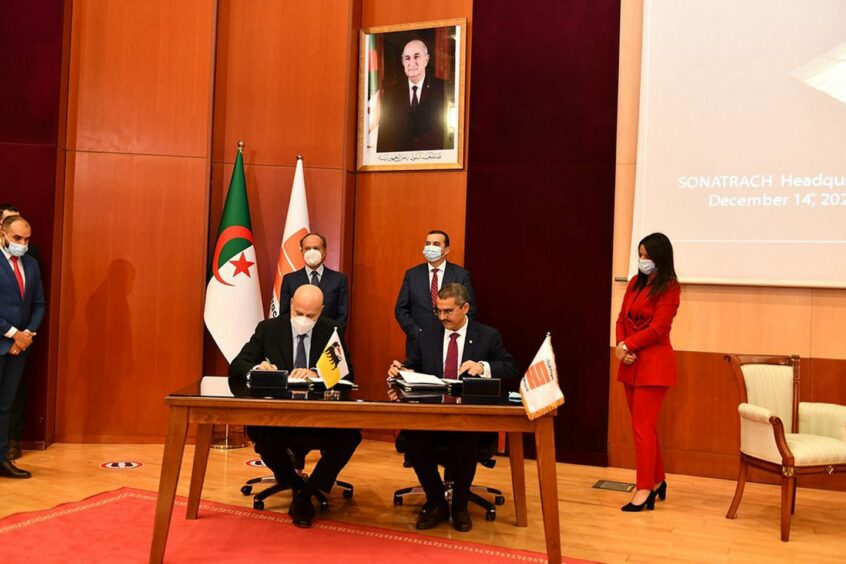 Two men sign documents at a table